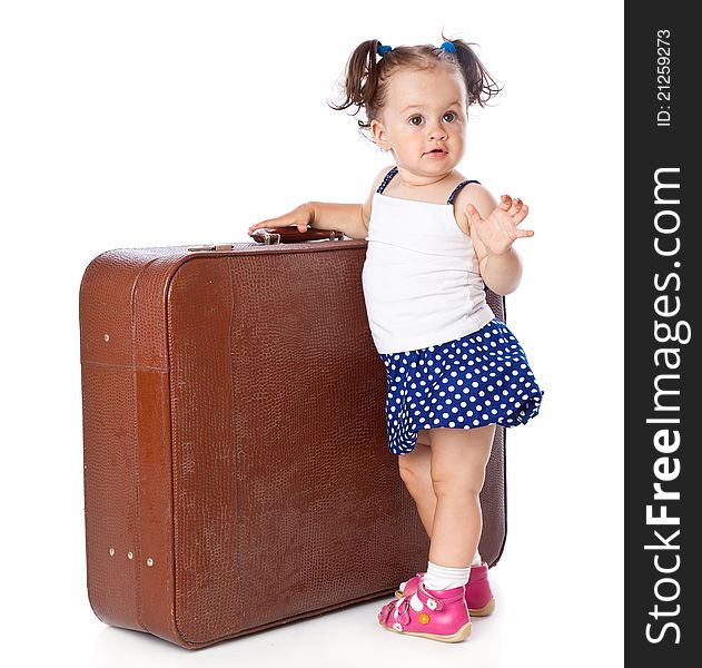 A little girl is standing near the suitcase . Isolated on a white background