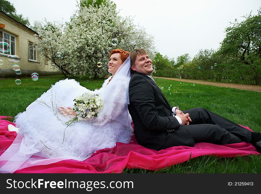 Happy bride and groom at wedding walk in spring cherry garden in rainy weather. Happy bride and groom at wedding walk in spring cherry garden in rainy weather