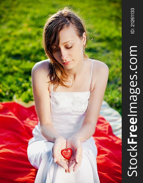 Bride holding in her hands red heart - symbol of love. Bride holding in her hands red heart - symbol of love