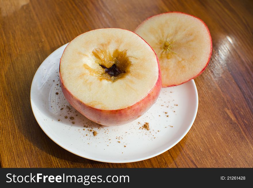 Baked apple with brown sugar and cinnamon on a white decorated plate