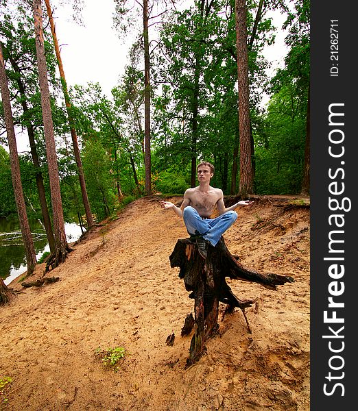 young guy meditates, sitting on a stub