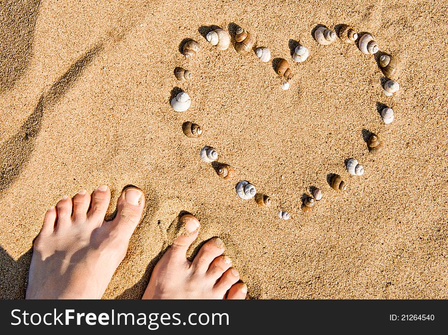 Image of the heart on sand. Ð¡ockleshells, feet. Image of the heart on sand. Ð¡ockleshells, feet
