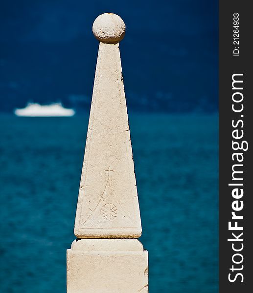 Cathedral of Supetar marking carved in stone sculpture with blue sea and ship in blurred background. Cathedral of Supetar marking carved in stone sculpture with blue sea and ship in blurred background