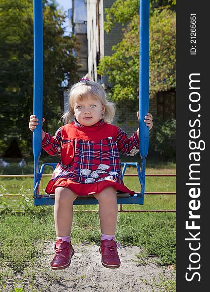 Adorable little girl having fun on a swing in summer