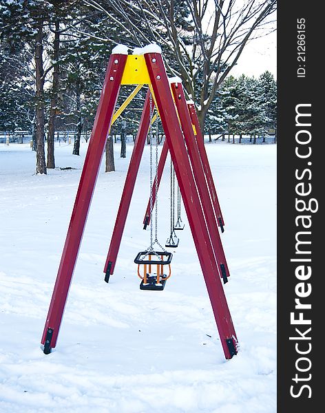 An empty children swings construction in a winter, snowy park. An empty children swings construction in a winter, snowy park