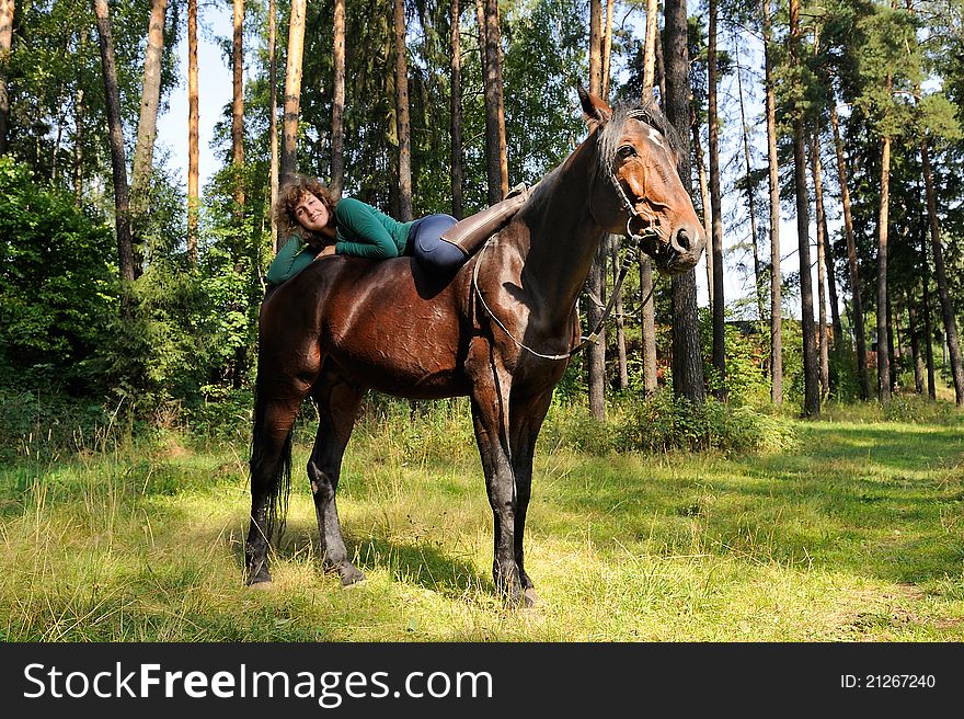 Smiling girl lies on horseback and coomunicats with her horse. Smiling girl lies on horseback and coomunicats with her horse