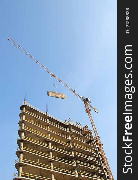 Crane Lifts The Plate  Against The Blue Sky