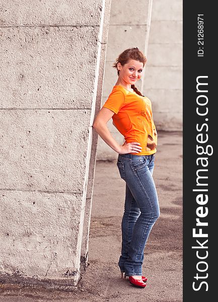 Full lenght shot of young woman against concrete wall. Full lenght shot of young woman against concrete wall