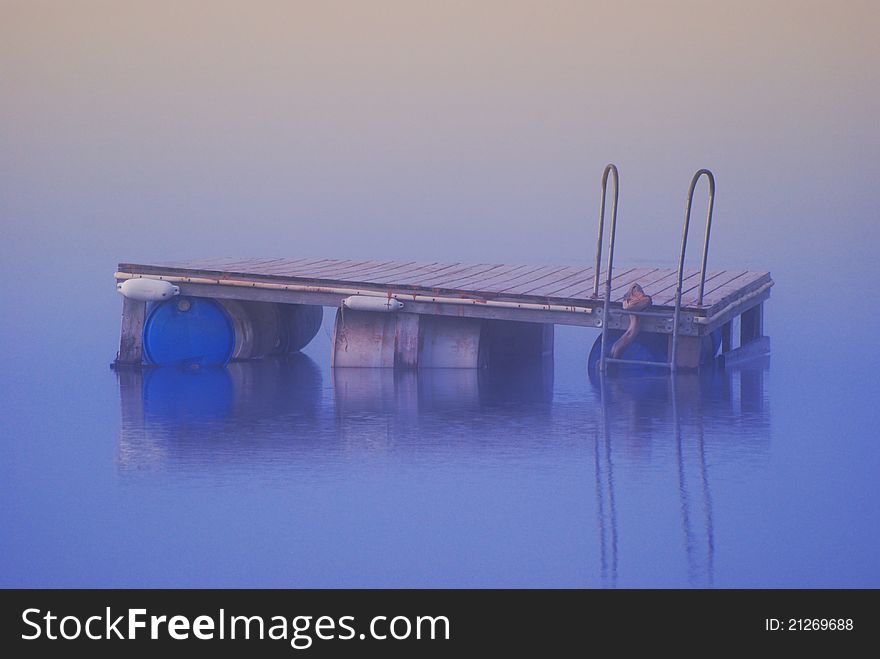 Dock floating on a glassy lake in the misty morning. Dock floating on a glassy lake in the misty morning