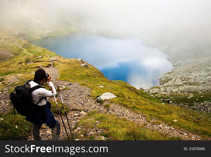 Hiker Taking Photos At Capra Lake In Fagaras