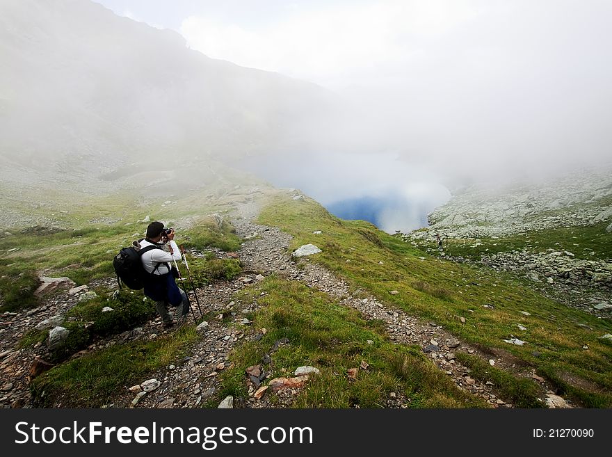 Hiker Taking Photos At Capra Lake In Fagaras