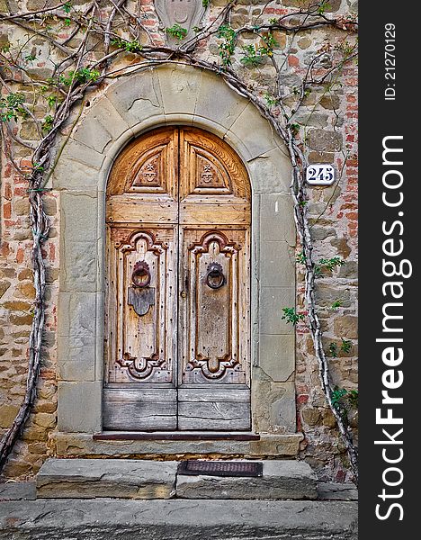 Old wooden door and brick wall in Tuscan village