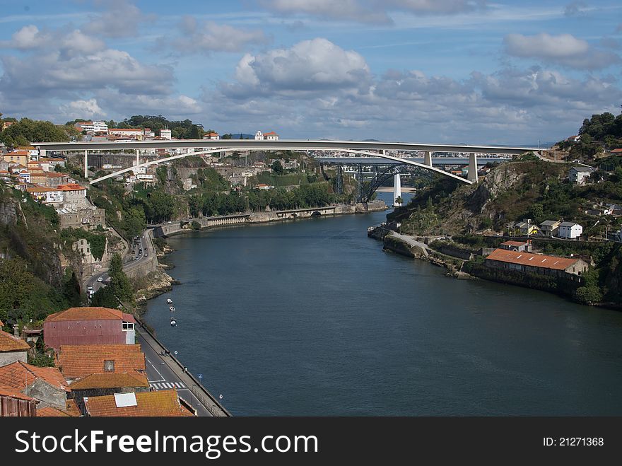 Porto, a city named for its importance as a shipping port in Portugal. A white bridge arcs over the main river of the city. Porto, a city named for its importance as a shipping port in Portugal. A white bridge arcs over the main river of the city.