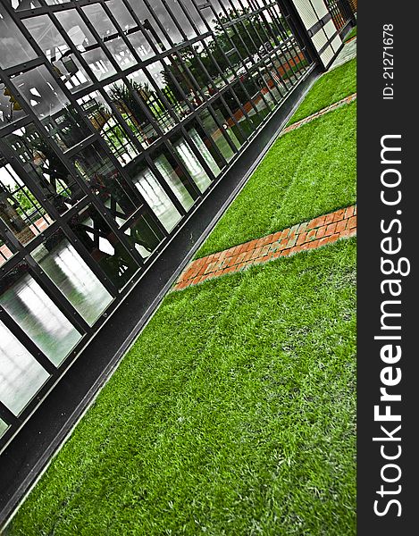 A photo of a glass wall with steal beams, and clean cut grass. A photo of a glass wall with steal beams, and clean cut grass.
