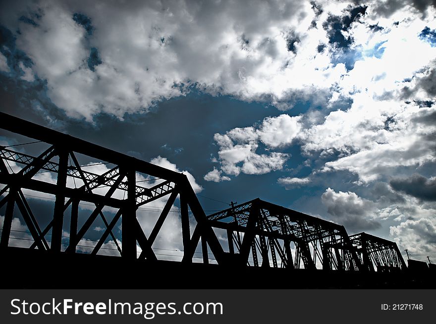 A bridge silo-wet with the sky and clouds in the background.