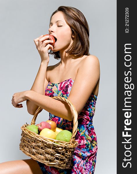 Girl with a basket of fruit eating an apple