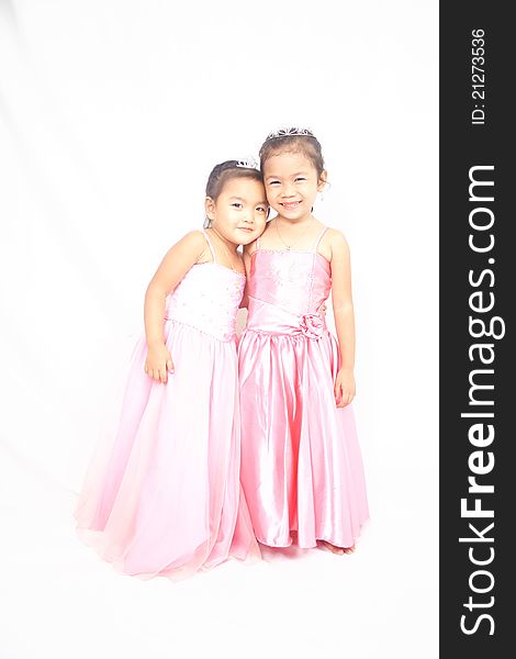 Two asian girls in pink clothes with crowns posing and smiling. Two asian girls in pink clothes with crowns posing and smiling