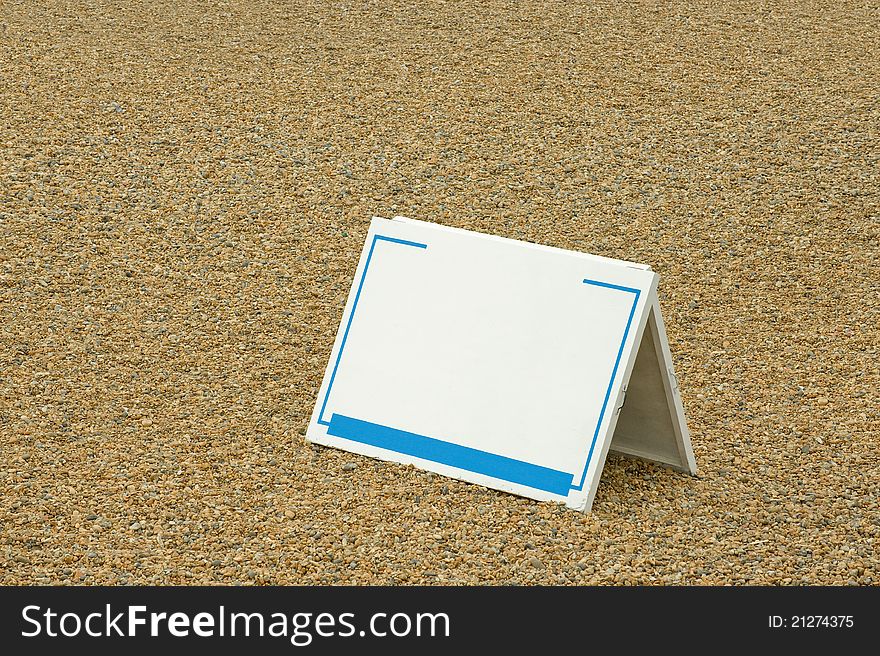 Blank sign copy-space template on a pebbled beach