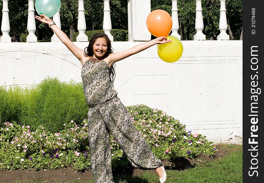 Joyful pregnant girl with colorful balloons walking in park