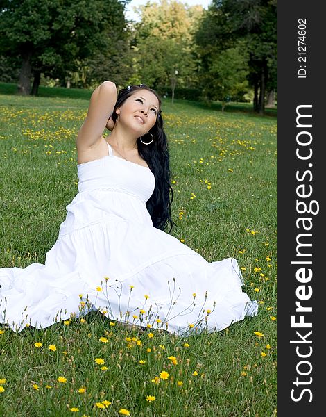 Beautiful pregnant girl sitting on grass among flowers