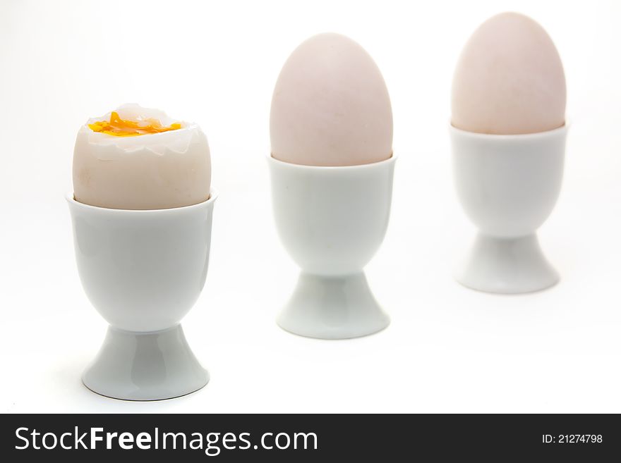 Three boiled eggs in egg cups against a white background. Three boiled eggs in egg cups against a white background