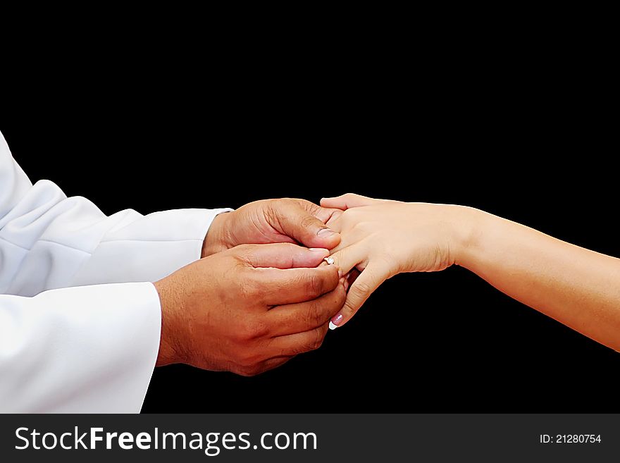 Wedding ceremony moment where the groom places the wedding ring on the brides finger. Wedding ceremony moment where the groom places the wedding ring on the brides finger.