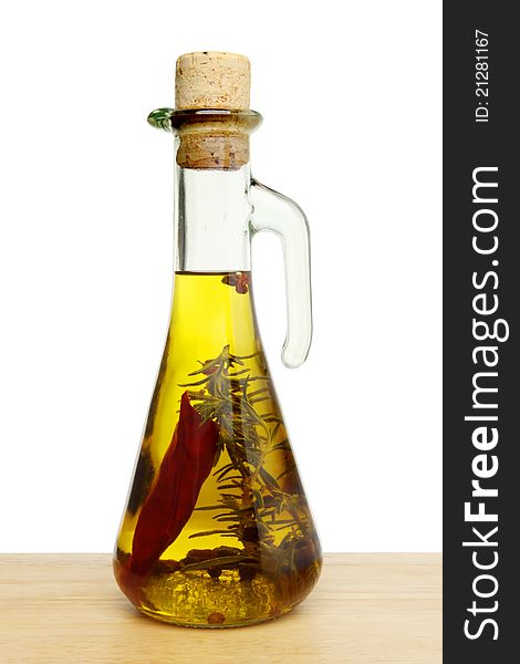 Flavoured olive oil in a glass jar on wood against a white background. Flavoured olive oil in a glass jar on wood against a white background