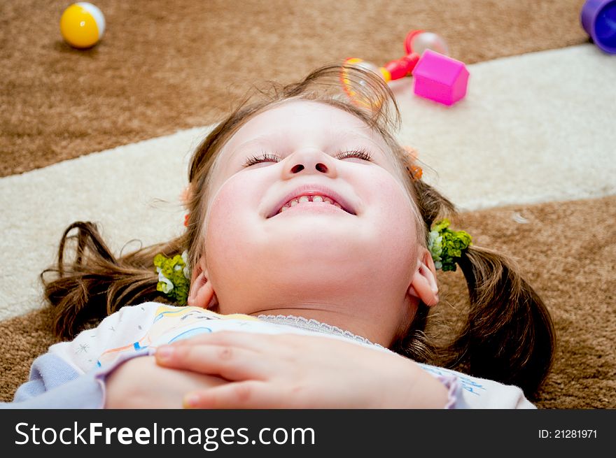 A little girl lying on the rug and smiling. A little girl lying on the rug and smiling