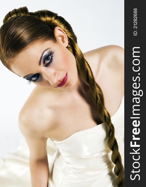 Beautiful young woman with extremly long eyelashes, and nice make up, with long hair in a wedding dress looking up, before a white background on a studio shot. Beautiful young woman with extremly long eyelashes, and nice make up, with long hair in a wedding dress looking up, before a white background on a studio shot