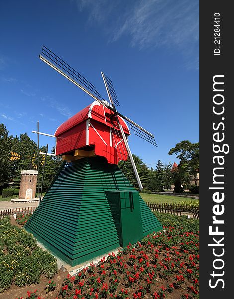 A red windmill on a grassplot in a park.