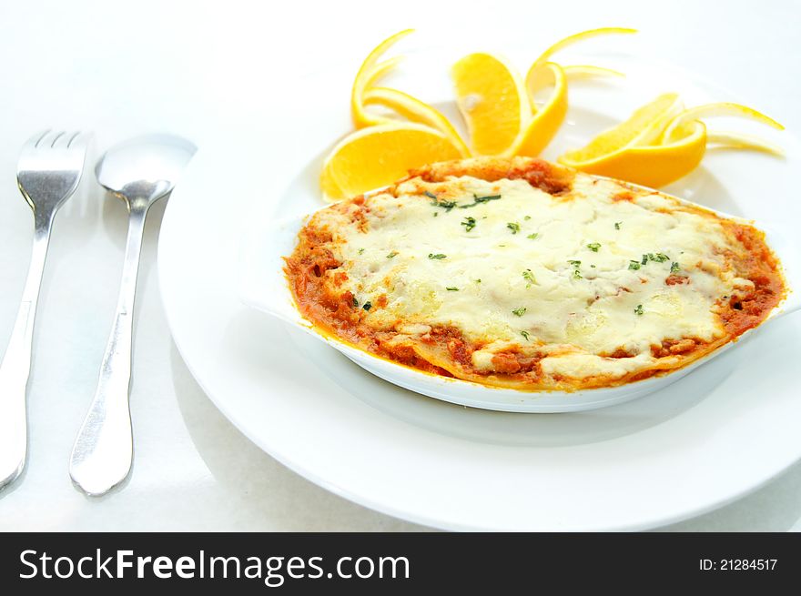 Delicious Italian lasagna with orange in background