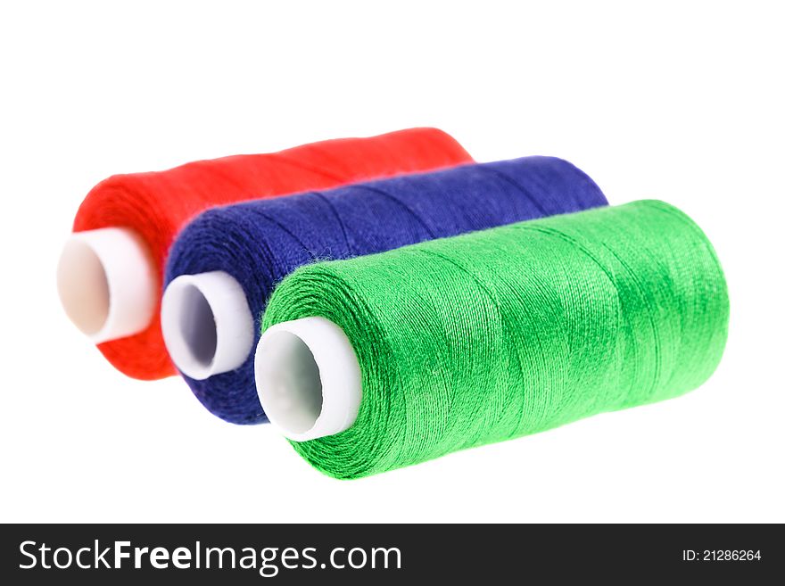 Photo of several coils of color threads on a white background (focus on green threads, small depth of sharpness)