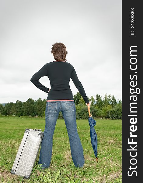 Woman on the grass with suitcase and umbrella