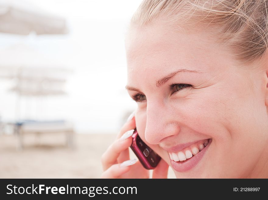 Young woman talking on the phone at the beach