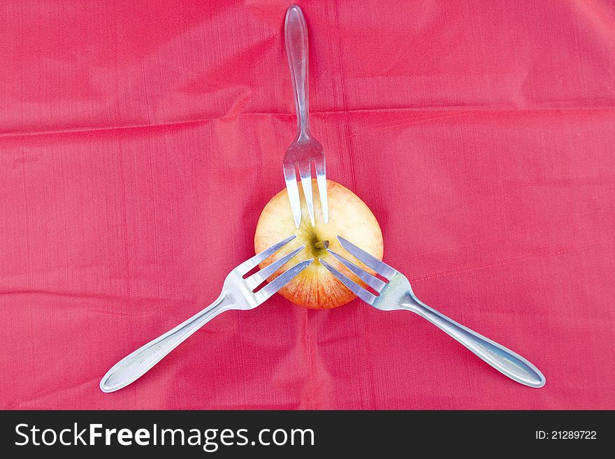 Golden-red apple on red with three dessert forks as for sharing healthy lifestyle. Golden-red apple on red with three dessert forks as for sharing healthy lifestyle.