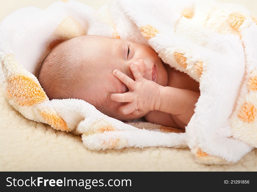 Baby lying and holding his head.