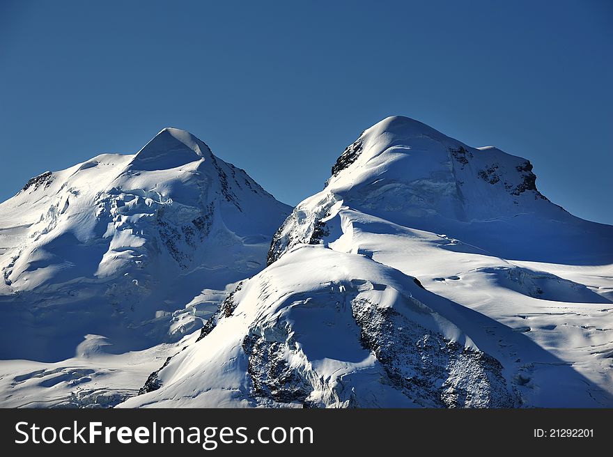 Summits of Castor and Pollux in the Swiss Alps, both 4000 meter peaks, seen from north. Summits of Castor and Pollux in the Swiss Alps, both 4000 meter peaks, seen from north
