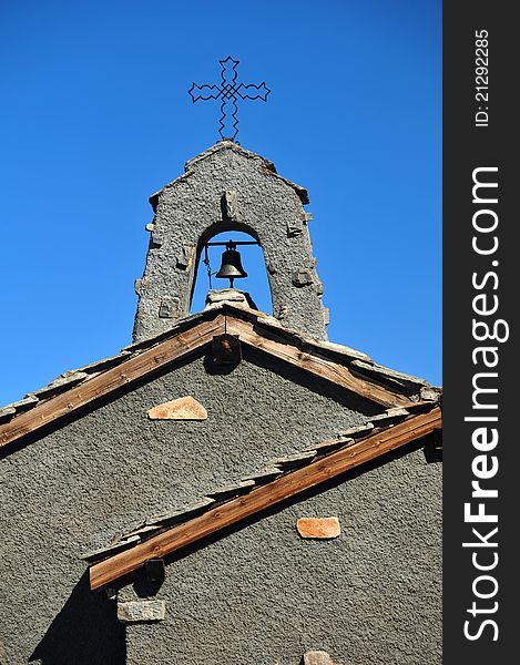 Holy cross, bell and roof top of a smal chapel against blue sky. Holy cross, bell and roof top of a smal chapel against blue sky