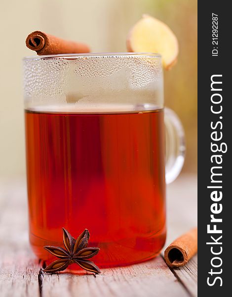 Red tea with cinnamon sticks on rustic wood