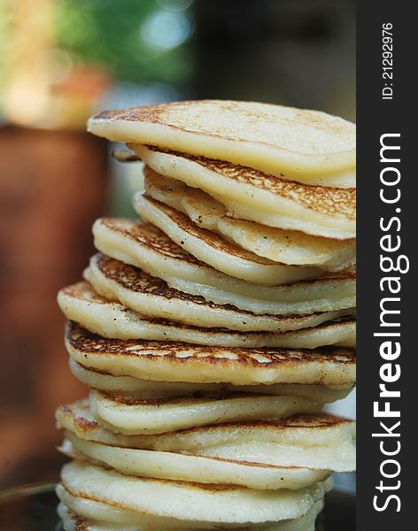 High pile of thick russian pancakes for breakfast. Natural light, green background. High pile of thick russian pancakes for breakfast. Natural light, green background