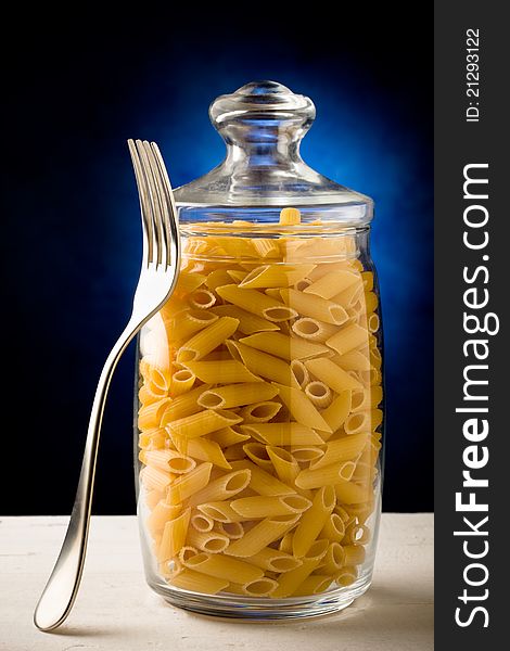 Photo of a glass container with raw pasta inside. Photo of a glass container with raw pasta inside