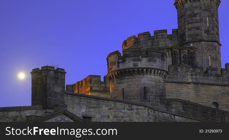 A detail of a Scottish castle with beautiful towers, with the moon in the background. A detail of a Scottish castle with beautiful towers, with the moon in the background.