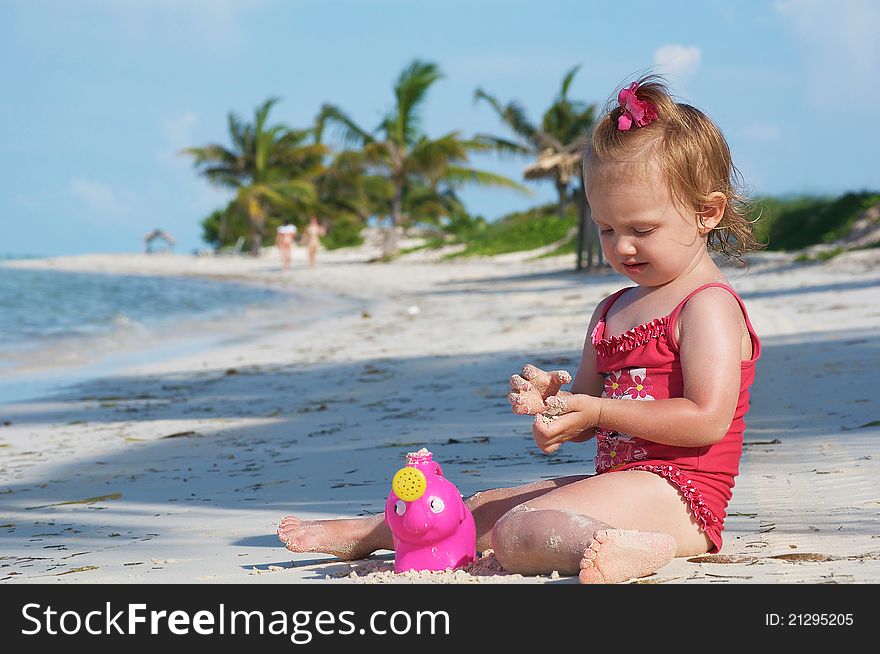 A baby girl is playing on the beach with her toys. A baby girl is playing on the beach with her toys