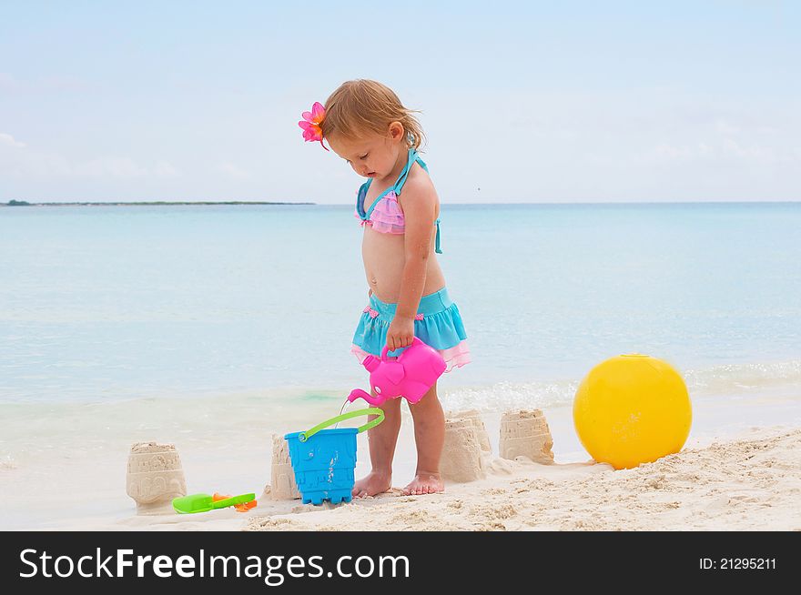 A baby girl is playing on the beach. A baby girl is playing on the beach