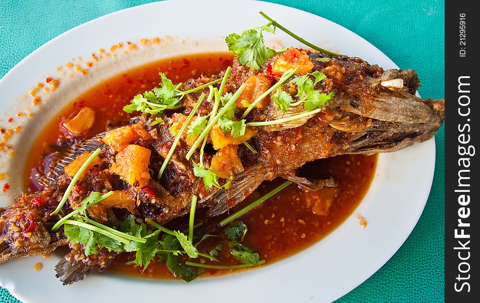 Fried grouper fish with sauce,sour and spicy on white plate,Thai style food.