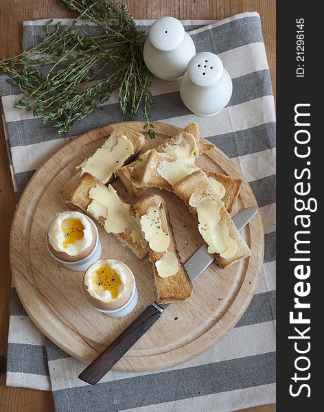 Soft-boiled eggs with buttered soldiers on a wooden board. Soft-boiled eggs with buttered soldiers on a wooden board