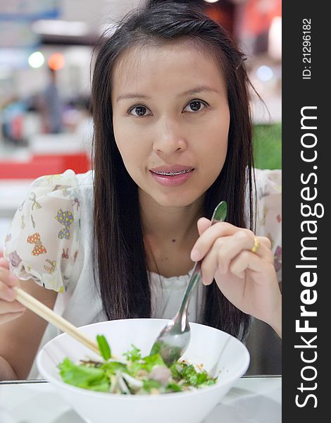 Young woman eating a noodle