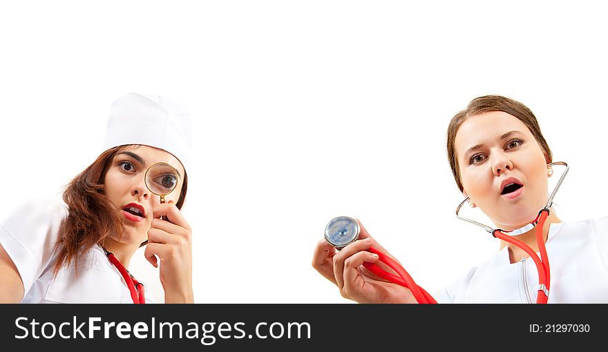 Two very surprised nurse doing a medical examination. One looks through a magnifying glass, the other holding a stethoscope. Two very surprised nurse doing a medical examination. One looks through a magnifying glass, the other holding a stethoscope