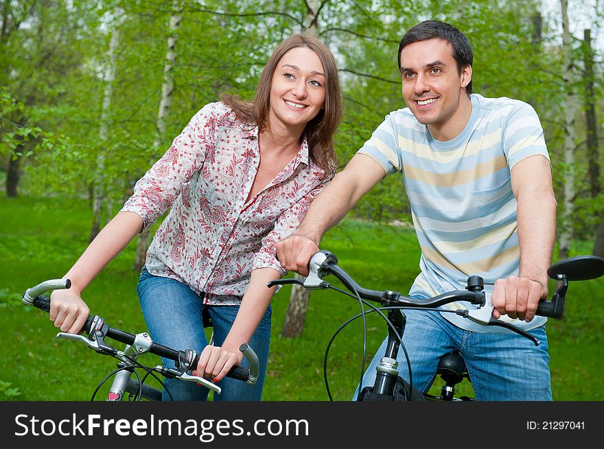 Happy young couple riding bicycles in a park