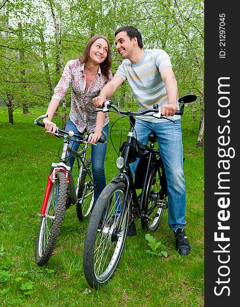 Happy young couple riding bicycles in a park